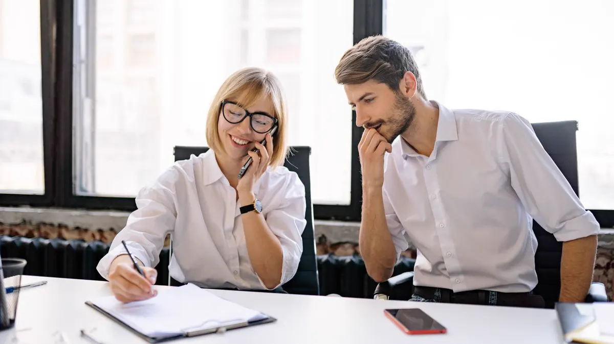 Office team member answering a customer call and taking notes — the front-desk work an AI receptionist covers for HVAC companies 24/7