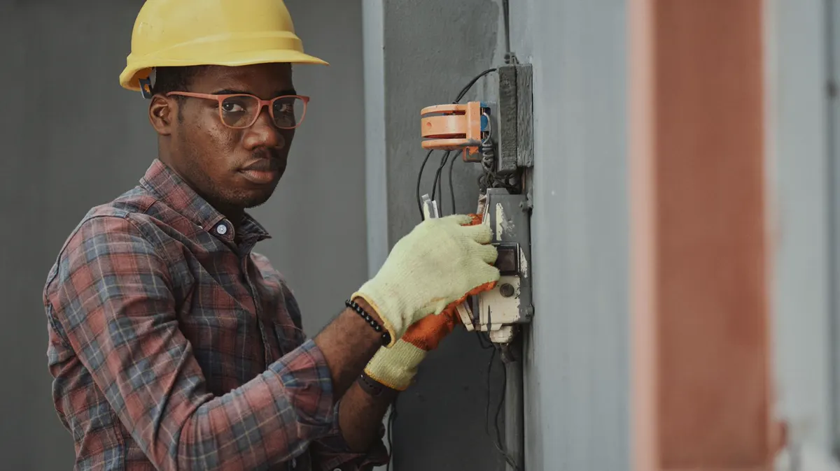 Field technician in a hard hat working on site, hands busy — unable to answer the phone while the AI receptionist takes the call