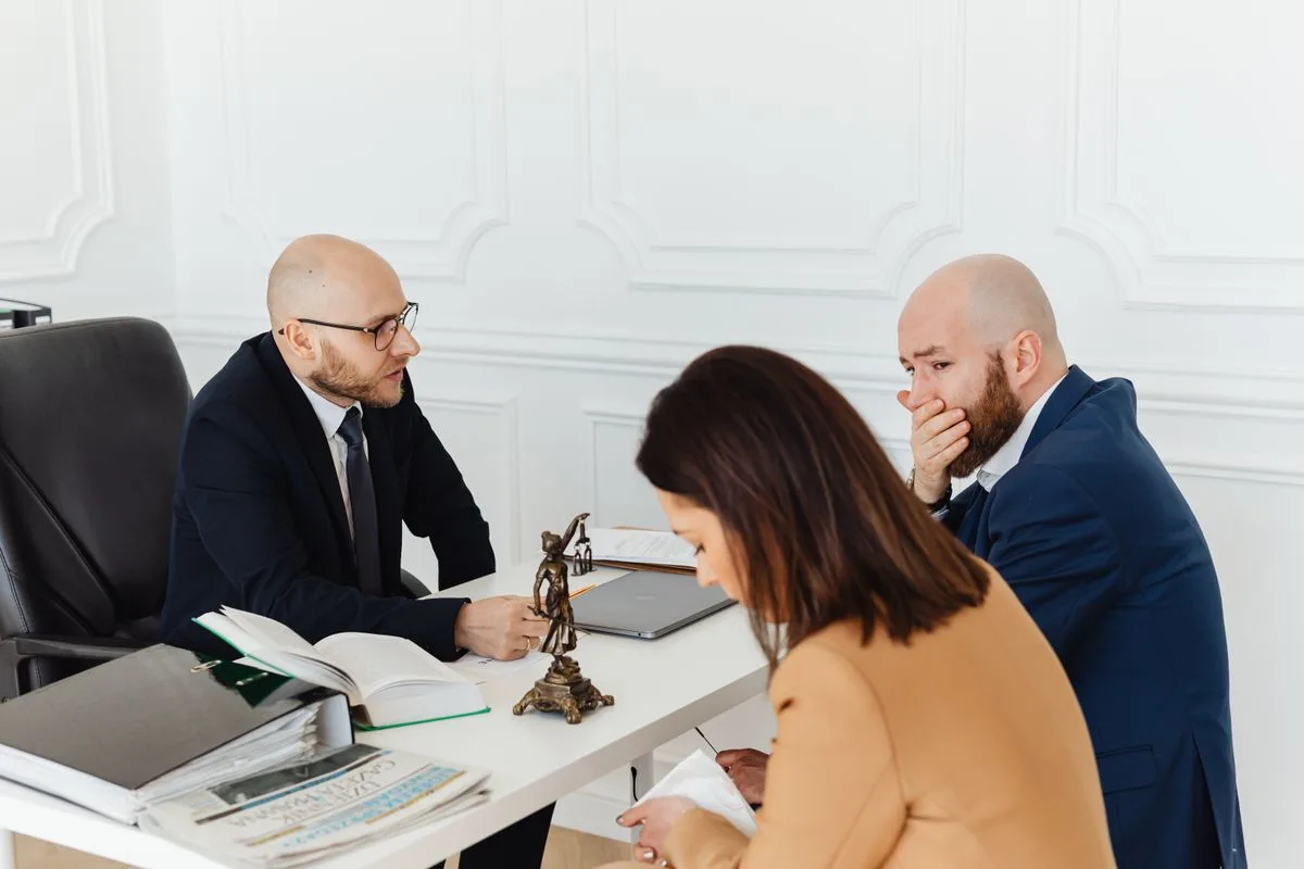 A serious legal consultation between a lawyer and clients in a professional office — the kind of booked consultation an AI receptionist for law firms fills the calendar with