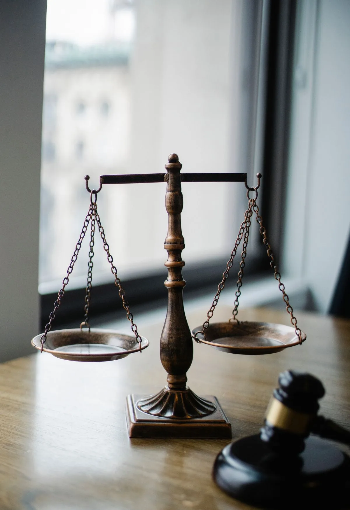Scales of justice and gavel on a lawyer's desk in a bright law office — an AI receptionist for law firms answers intake calls while attorneys are in court