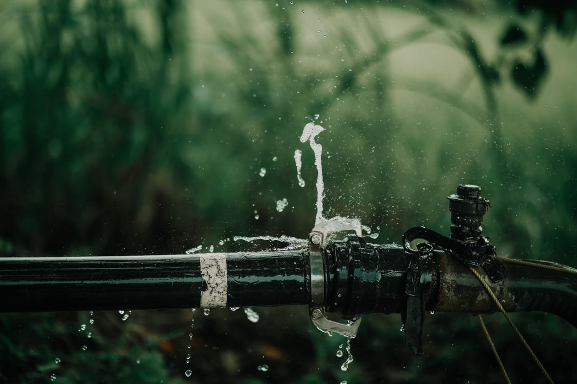 Leaking water pipe spraying water outdoors — the kind of plumbing emergency an AI receptionist for plumbers answers at any hour